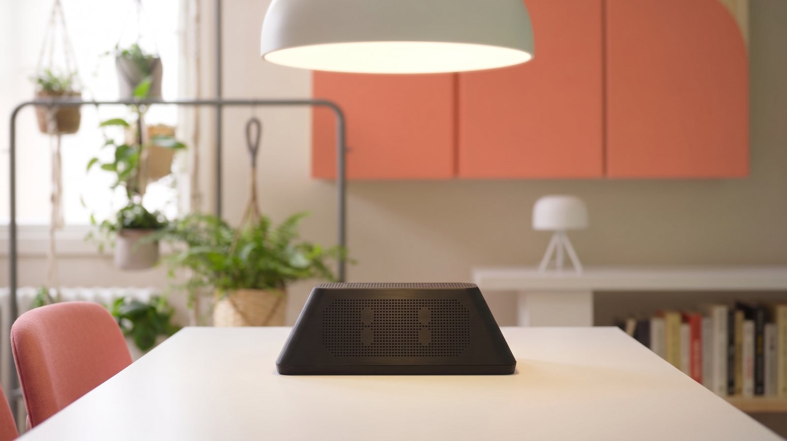 The Sudo home device on a dining table in a warm, plant-filled home.